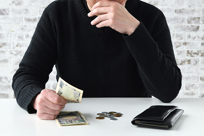 お金を片手に考える男性